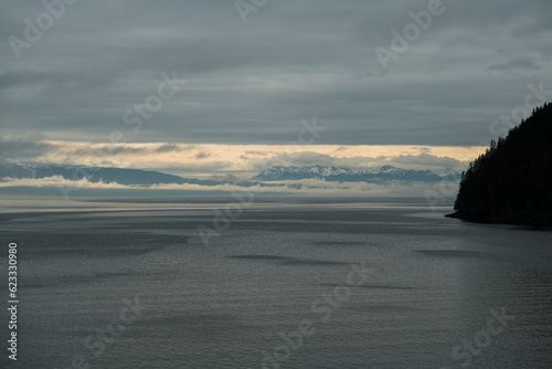 Magic mystic cloudscape around Glacier Mountain Range on Baranof Island near Hoonah, Icy Strait Point in Alaska during sunrise with tree silhouettes dusk from cruise ship liner photo
