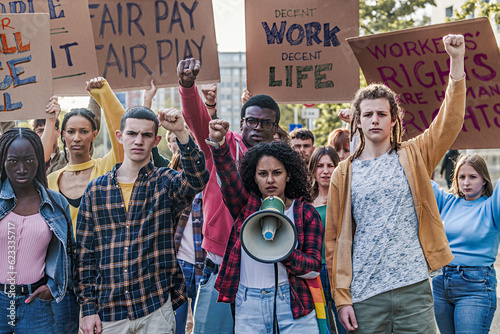 Canvas Print Multiethnic Youth Protesting for Decent Work and Life - A group of multiethnic youth protesting for fair pay and work access, raising fists