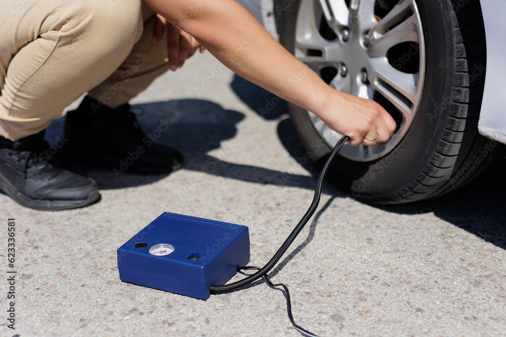 Obraz premium Man checking air pressure and filling air in the tires of car