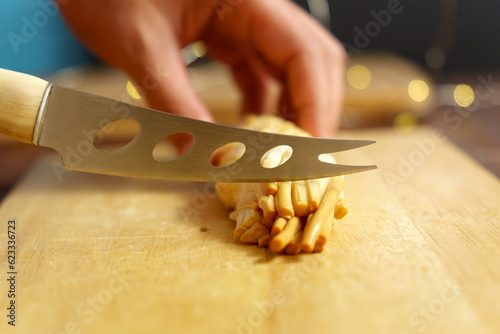 Cuts cheese in close-up with a cheese knife. Selective focus