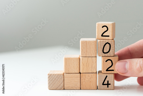 2024 new year symbol. Wooden cubes with number 2023 on a beautiful background from dollar bills, copy space. Business and 2023 new year concept.
