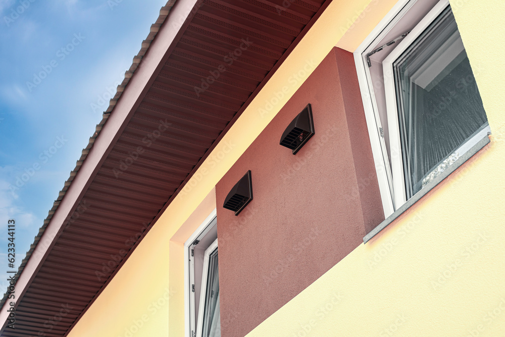 Fototapeta premium The outer side of the wall of the house with ventilation holes for the air recuperator. Daytime outdoors from low angle view.