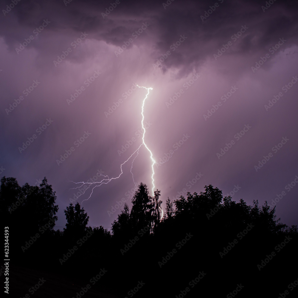 beautiful lightning during a thunderstorm at night in a forest that caused a fire, against a dark sky with rain