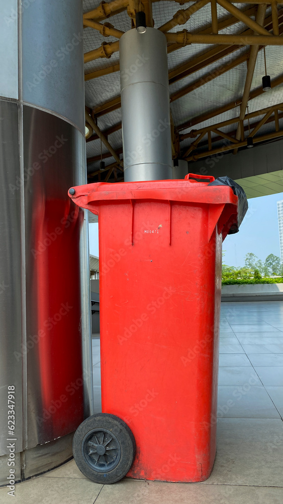 Red recycling bin stands outdoor. 