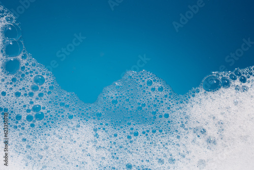 Fotografija Detergent foam bubble on water. Blue background, Soap sud