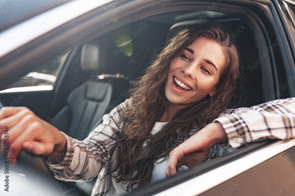 Portrait of a beautiful smiling woman in a car looking out of the window