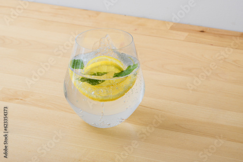 Szklanka wody gazowanej z cytryną i miętą stojąca na kuchennym blacie