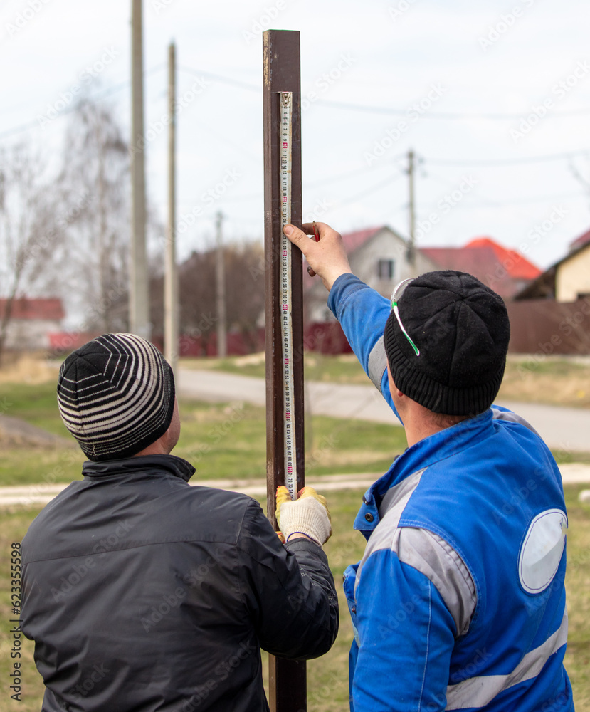 Obraz premium Workers install a metal profile fence