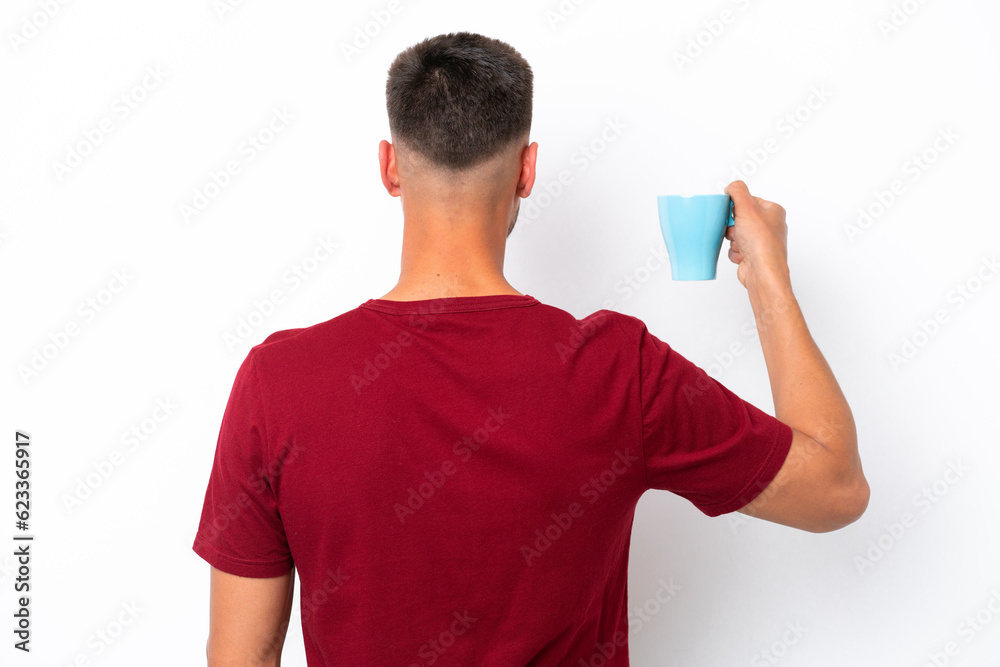 Young caucasian man holding cup of coffee isolated on white background in back position Young caucasian man holding cup of coffee isolated on white background in back position