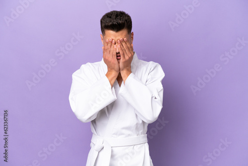Young caucasian man doing karate isolated on purple background with tired and sick expression © luismolinero