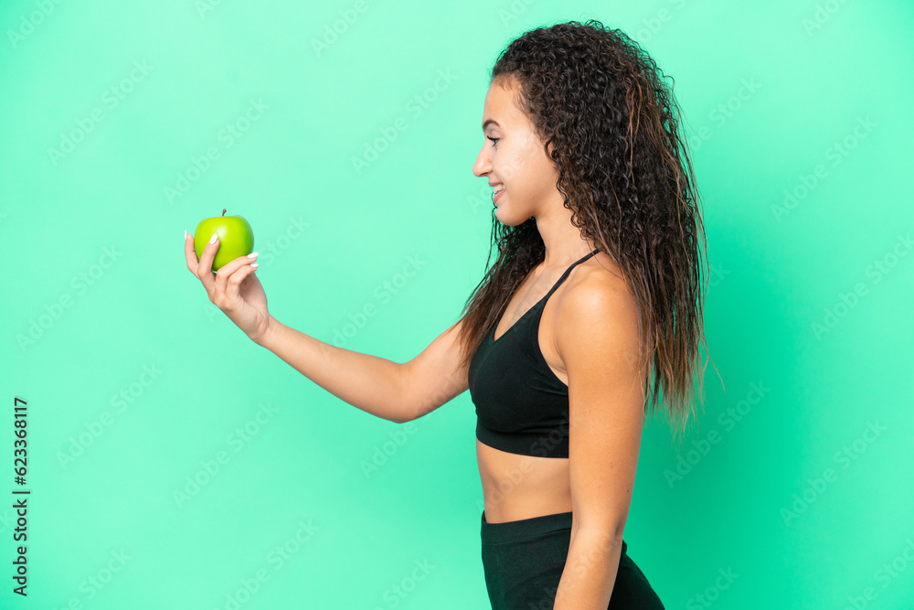 Young Arab woman with an apple isolated on green background with happy expression Young Arab woman with an apple isolated on green background with happy expression