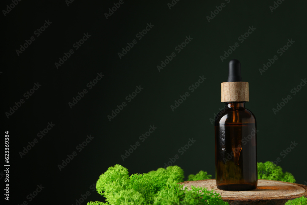 Moss, bottle of serum on wooden stand on dark green background, space for text