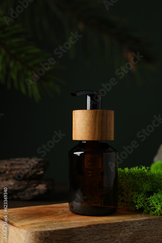 Dispenser on wooden stand, moss, on dark green background