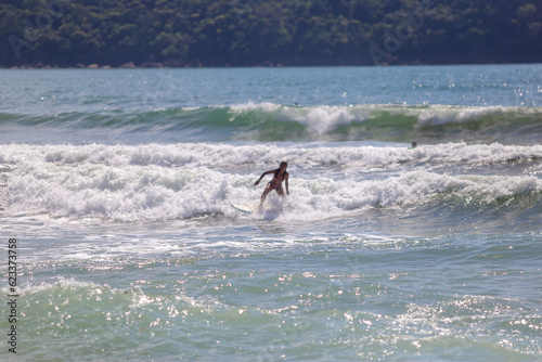 Jovem e linda, a mulher brasileira mostra toda sua destreza ao aproveitar o mar na praia paradisíaca para surfar. Quebra barreiras e revela que as mulheres também mandam muito bem nesse esporte. photo