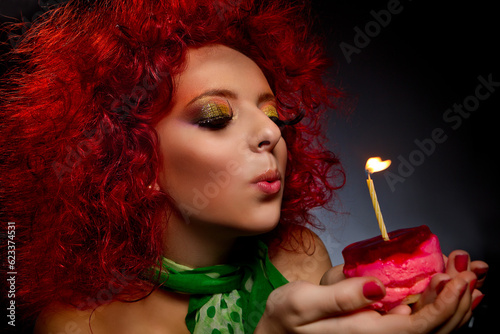 Gamour girl with cake blowing out candle in her birthday photo