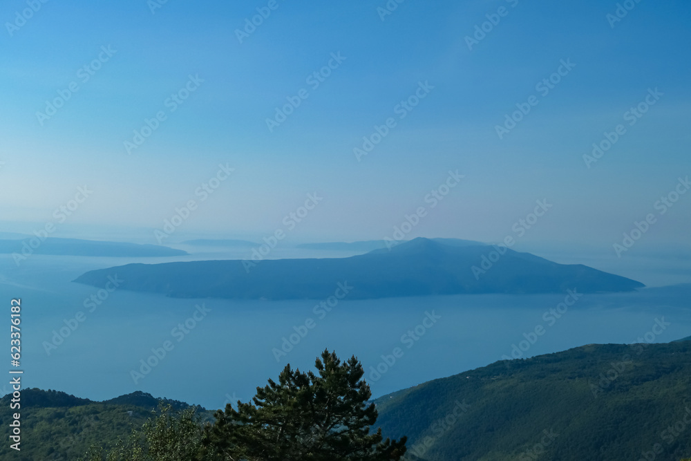 A panoramic view on the Mediterranean Sea in Croatia from Vojak. The mountain is overgrown with lush green plants. Few islands in the back. Early morning hiking by the sea. Clear, blue sky. Remedy