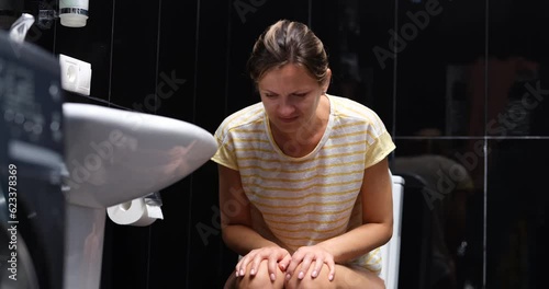 A woman is sitting on the toilet, having difficulty defecation. Bowel problem, constipation. Inflammation of hemorrhoids