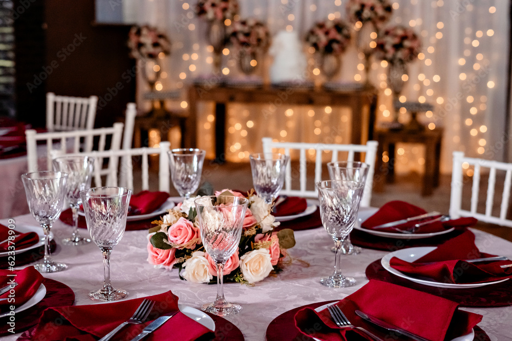 a round table decorated with a flower arrangement, glass bowls, plates and red napkins a round table decorated with a flower arrangement, glass bowls, plates and red napkins