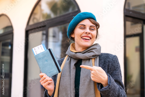 Brunette woman holding a passport at outdoors and pointing it © luismolinero