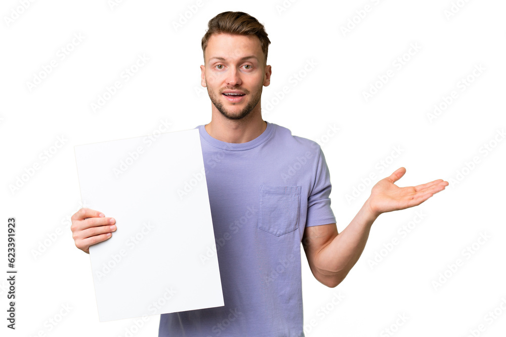 Young blonde caucasian man over isolated background holding an empty placard with surprised expression Young blonde caucasian man over isolated background holding an empty placard with surprised expression