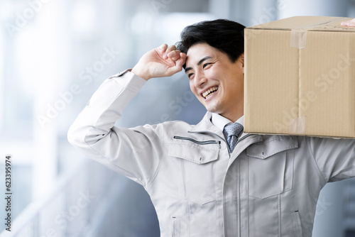 Also for the main visual! Handsome or smiling Asian (Japanese) worker carrying a cardboard box. For hiring or changing jobs in shipping and logistics.