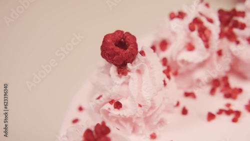 The pastry chef decorates the cake with freeze-dried raspberries on the left. The work of a pastry chef photo