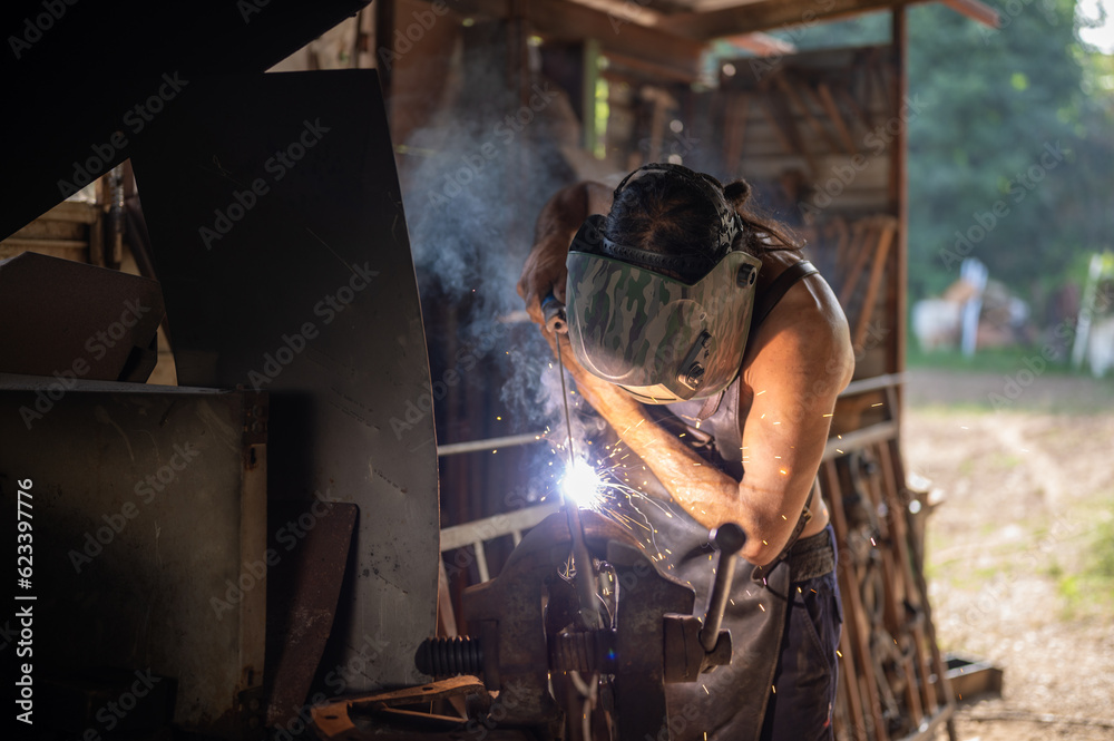 Blacksmith welding a piece of iron in his home workshop. Blacksmith welding a piece of iron in his home workshop.