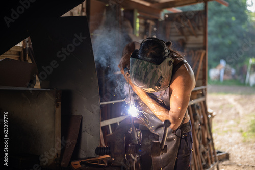 Blacksmith welding a piece of iron in his home workshop.