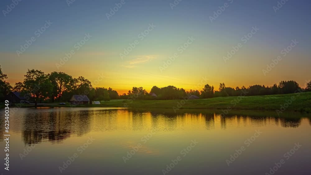 Timelapse of a lake at sunset with blue and yellow sky and clouds reflected in the water. Timelapse of a lake at sunset with blue and yellow sky and clouds reflected in the water.