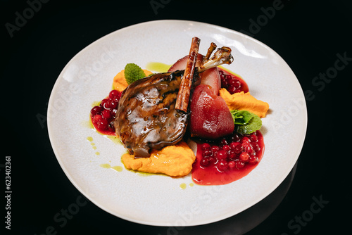 Tender duck leg with cranberry sauce on a black background