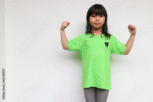 Power girl. A cute confident girl looking at camera raised hand showing her bicep muscle