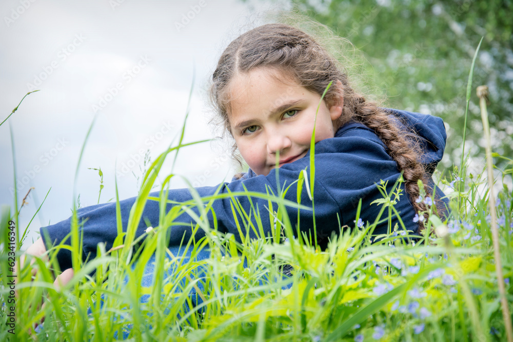 In the summer afternoon, on the river bank, a girl sits in tall grass. In the summer afternoon, on the river bank, a girl sits in tall grass.
