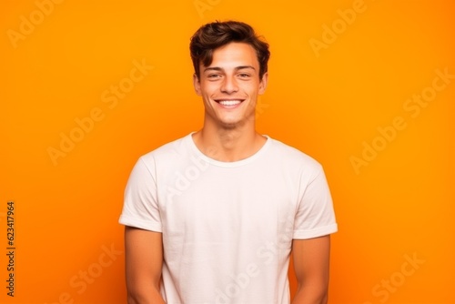 Medium shot portrait photography of a beautiful boy in his 30s wearing a casual t-shirt against a bright orange background. With generative AI technology