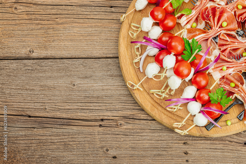 Set of picnic snacks on skewers. Jamon, mozzarella, cherry tomatoes, peas, fresh greens Set of picnic snacks on skewers. Jamon, mozzarella, cherry tomatoes, peas, fresh greens