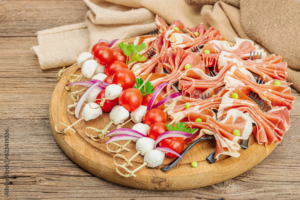 Set of picnic snacks on skewers. Jamon, mozzarella, cherry tomatoes, peas, fresh greens Set of picnic snacks on skewers. Jamon, mozzarella, cherry tomatoes, peas, fresh greens