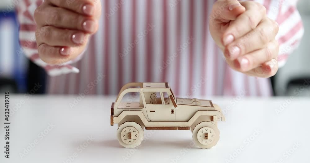 Female hands hugging and protecting toy wooden car 4k movie slow motion. Car insurance concept