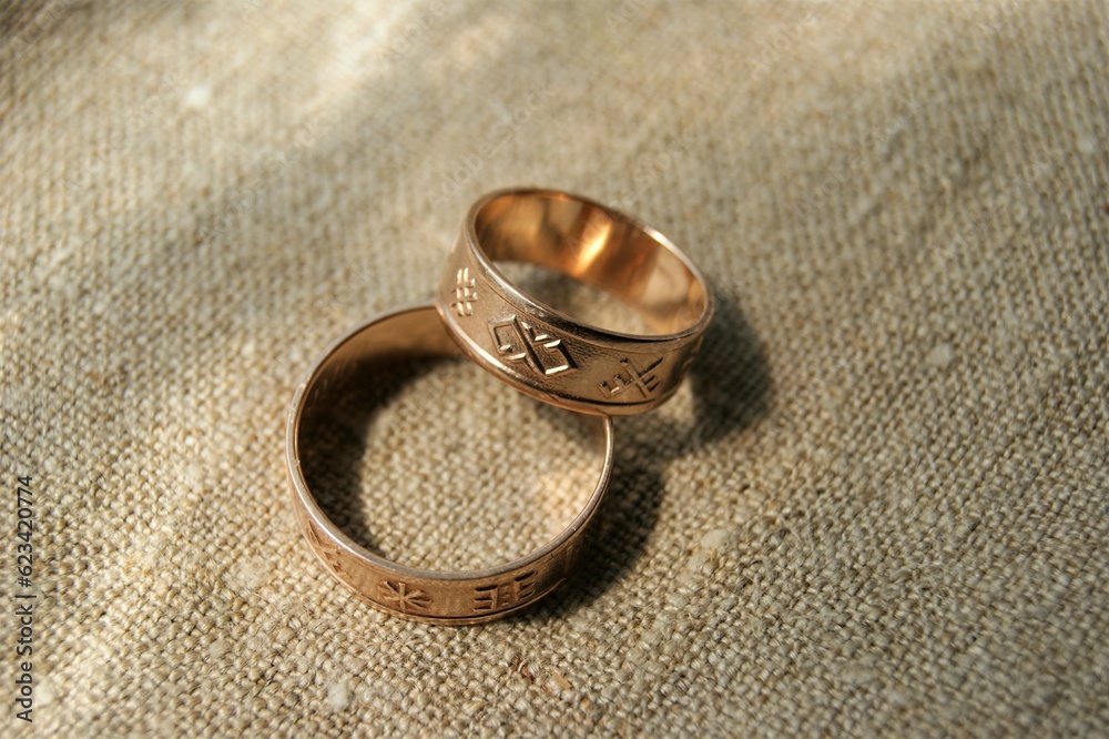 Latvian ancient symbols. Gold wedding rings with ancient symbols. Rings on linen fabric. Latvian ancient symbols. Gold wedding rings with ancient symbols. Rings on linen fabric.