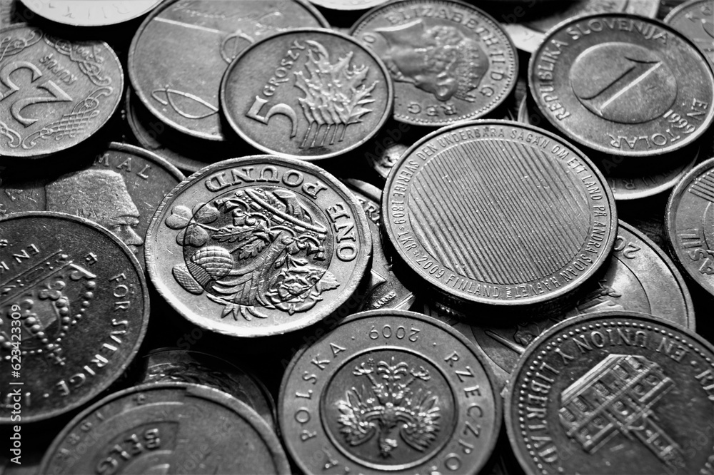 A fragment of a coin pile. Coins of different countries, black and white image. Background. - obrazy, fototapety, plakaty 