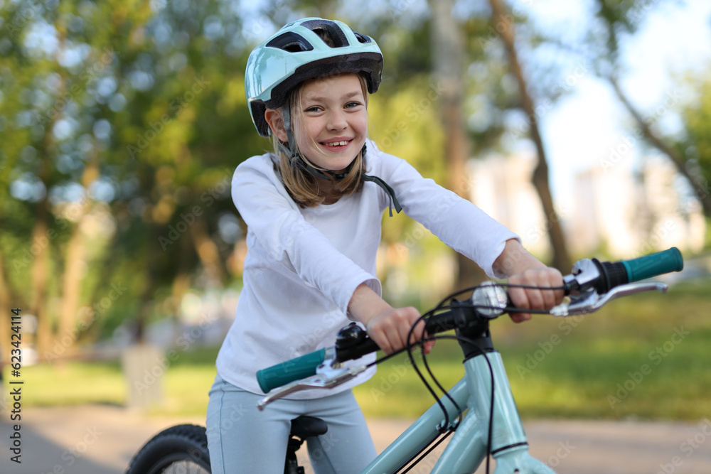 Portrait of a little girl in a helmet who enjoys a bike ride.