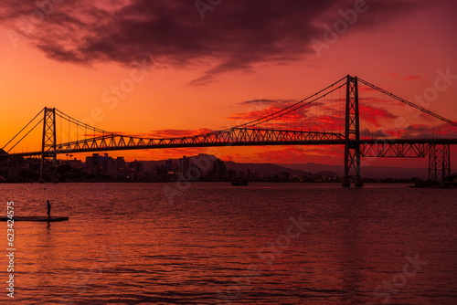 Silhouette of cable bridge with sunset sky and reflection on water in Florianopolis, Brazil
