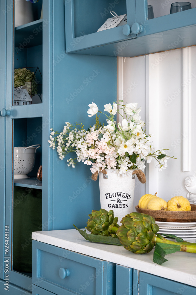 Vertical shot of white countertop with flowers and vegetables