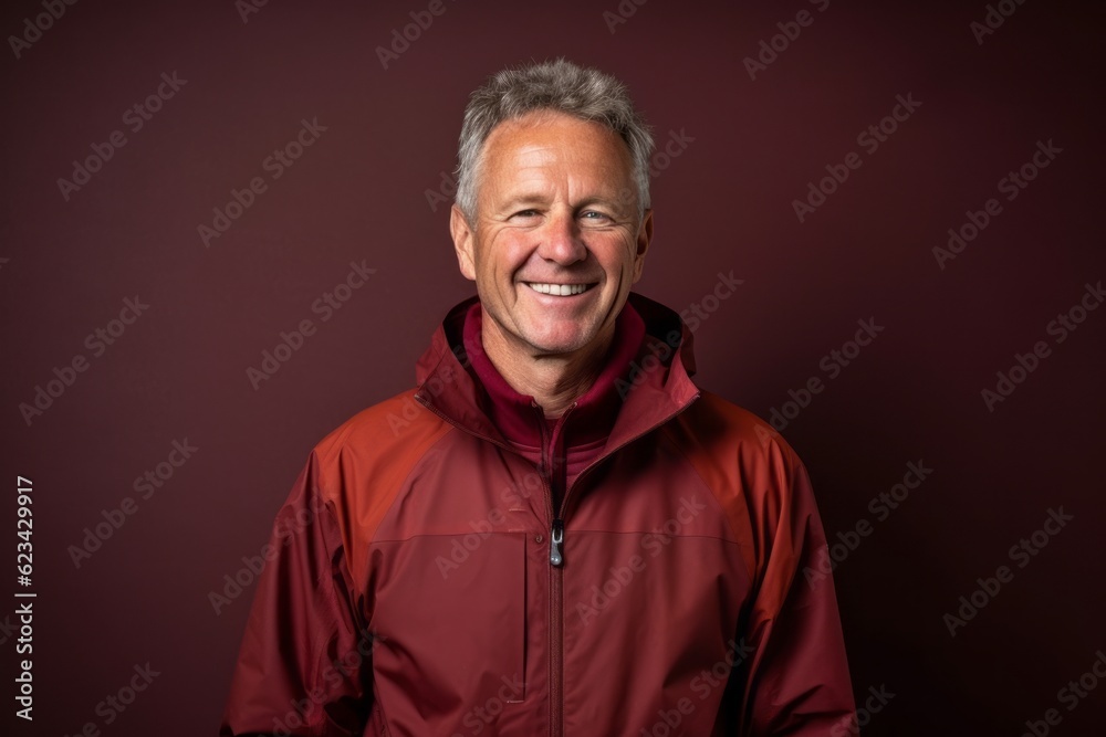 Lifestyle portrait photography of a grinning mature man wearing a lightweight windbreaker against a rich maroon background. With generative AI technology Lifestyle portrait photography of a grinning mature man wearing a lightweight windbreaker against a rich maroon background. With generative AI technology