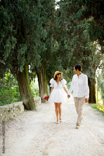 Stylish bride in short wedding dress and hat walking at Tuscany alley  © Natalia