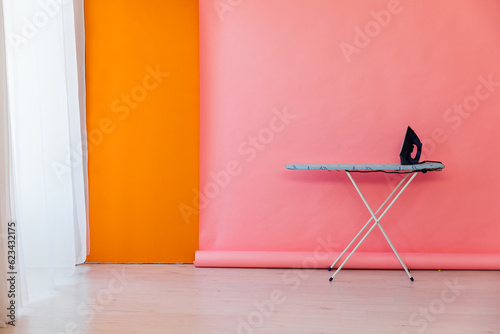 Interior Ironing Board Iron on Pink Orange Background