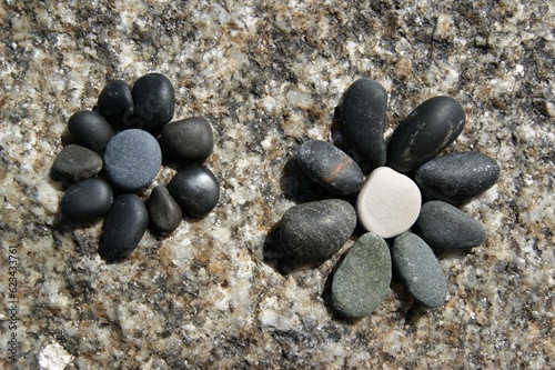 A flowers laid out of pebbles on a stone.