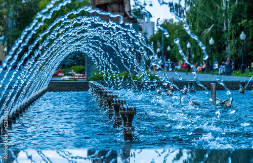Transparent water jets in the fountain on a summer day. © Сергей Лаврищев