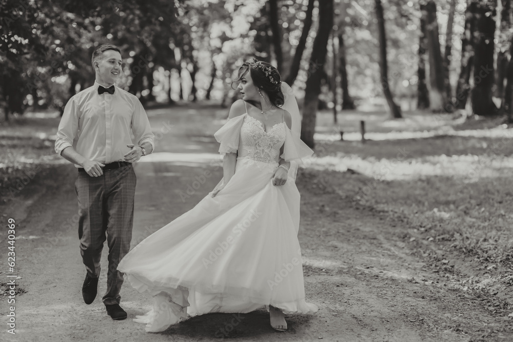 A wedding couple, a happy bride and groom are running in the park to the place of the wedding ceremony. Wedding concept A wedding couple, a happy bride and groom are running in the park to the place of the wedding ceremony. Wedding concept