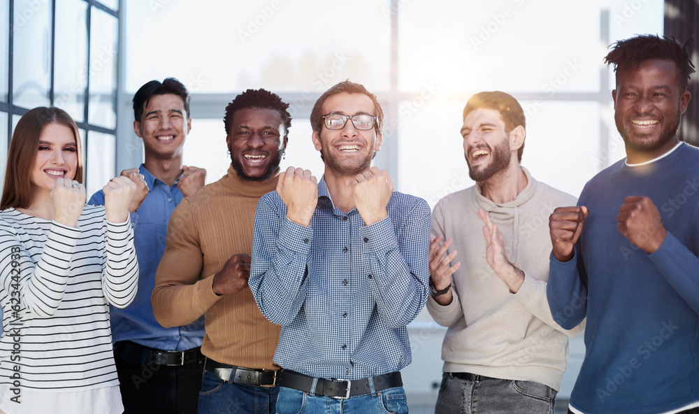 Fototapeta premium Group of happy managers rejoice at a successful deal by clenching their hands into fists and raising them up