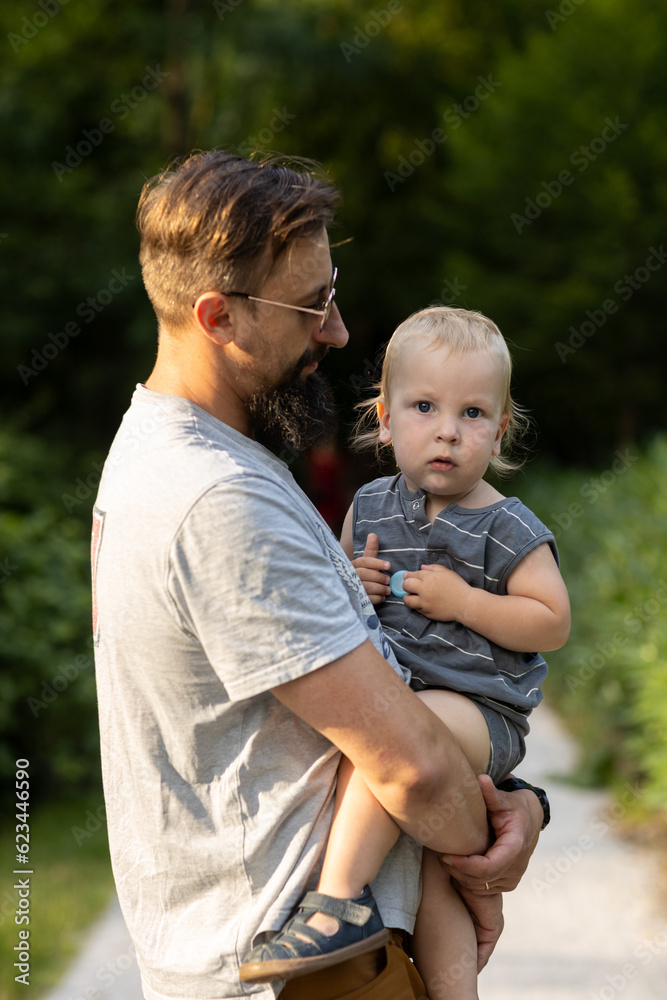 Fototapeta premium Young father with his little son walking in the park on a sunny day
