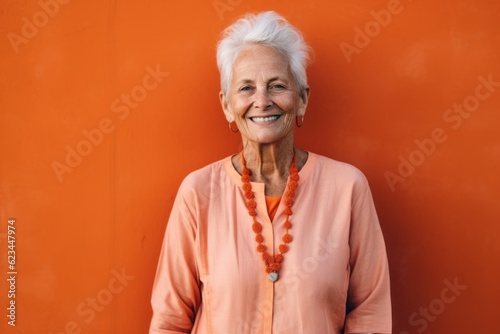 Lifestyle portrait photography of a satisfied old woman wearing a simple tunic against a pastel orange background. With generative AI technology